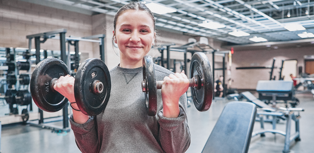 Woman does weight lifting rows in the MCC fitness center.