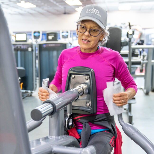 Woman works on strength training machine in the fitness center in the MCC.