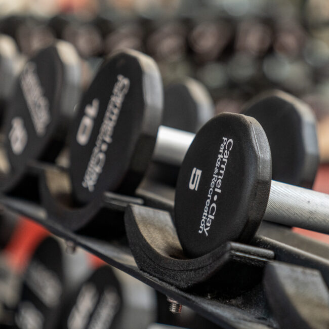 Free weights in the fitness center with the CCPR logo on them.