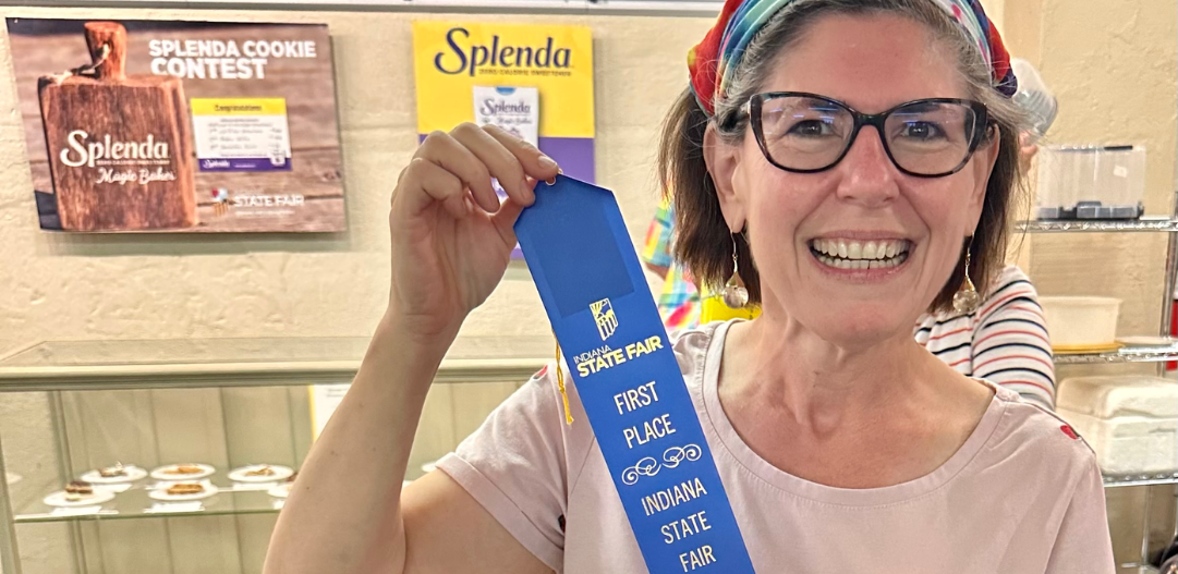 MCC Member Samantha A holding up her First Prize blue ribbon for her cupcakes at the State Fair.