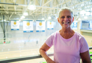 MCC member JoNell poses in front of the CCPR award banners in the gymnasium.